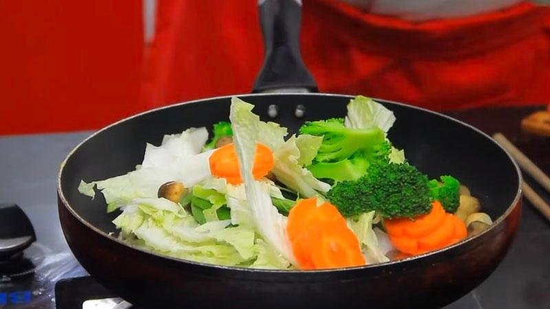 Sau đó cho cải thảo, cải ngọt, cà rốt, bông cải và nấm rơm vào cùng với một ít nước.