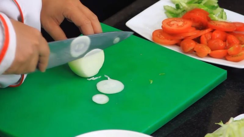 Hành tây lột vỏ, rửa lại với nước rồi cắt thành từng khoanh nhỏ, cho vào trong nước lạnh, ngâm 5 phút để loại bỏ mùi hăng của hành.